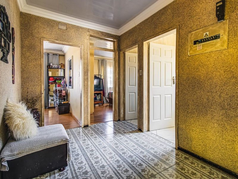 A central hallway featuring tiled flooring, coving, and access to multiple rooms, with an exposed electrical distribution board.