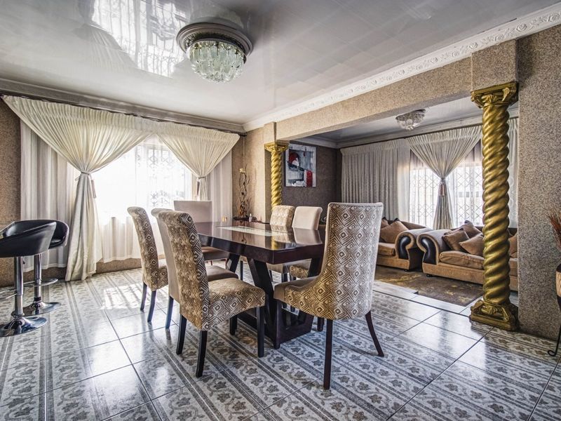 Open plan dining and living area featuring decorative columns, glossy ceiling finish, and patterned ceramic floor tiles.