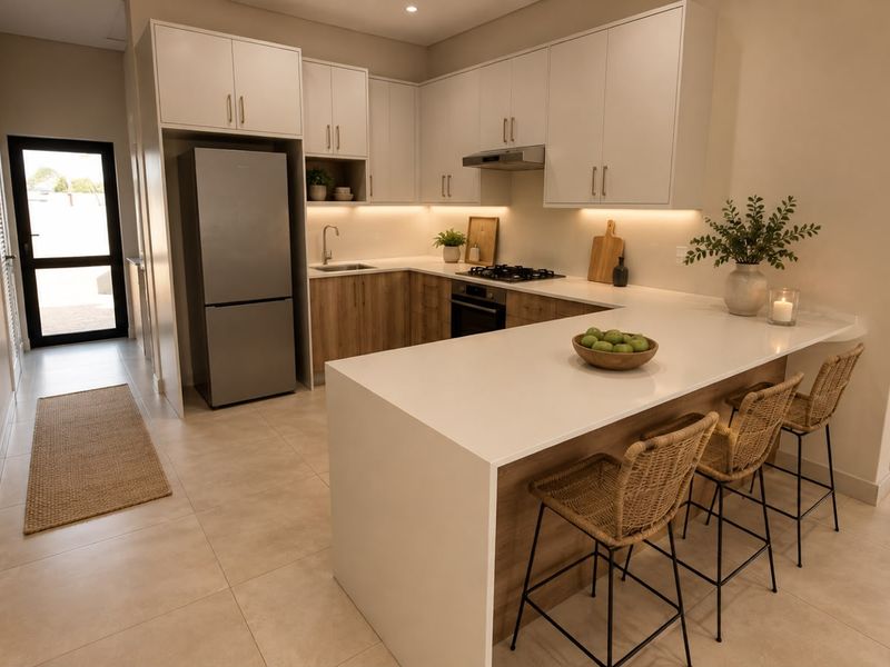Modern kitchen featuring sleek white and wood-tone cabinetry, stone countertops, a breakfast bar, and integrated appliances with warm under-cabinet lighting.