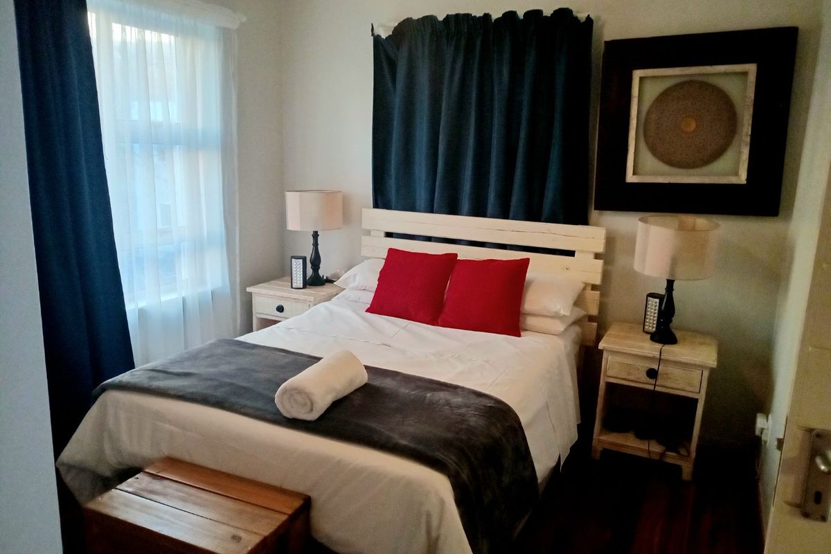 A cozy bedroom featuring dark timber flooring and neutral wall finishes, providing a comfortable and functional sleeping space.