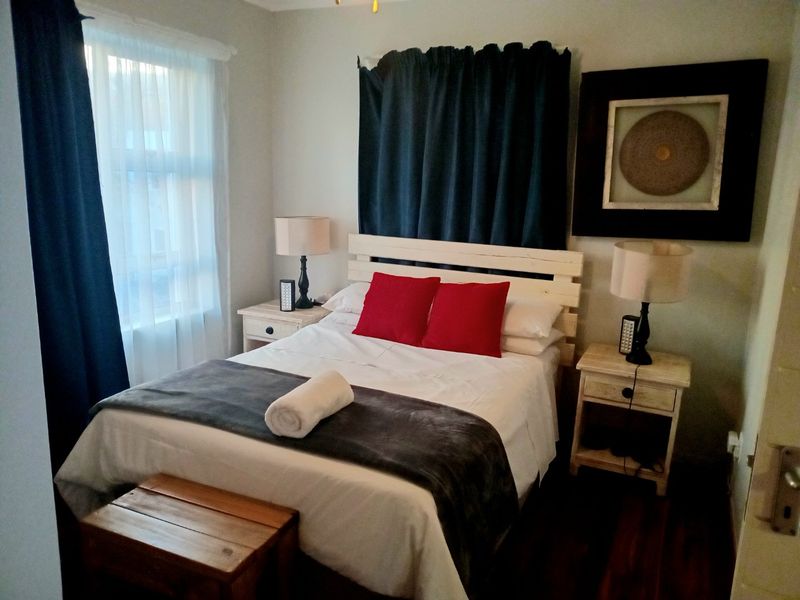 A cozy bedroom featuring dark timber flooring and neutral wall finishes, providing a comfortable and functional sleeping space.