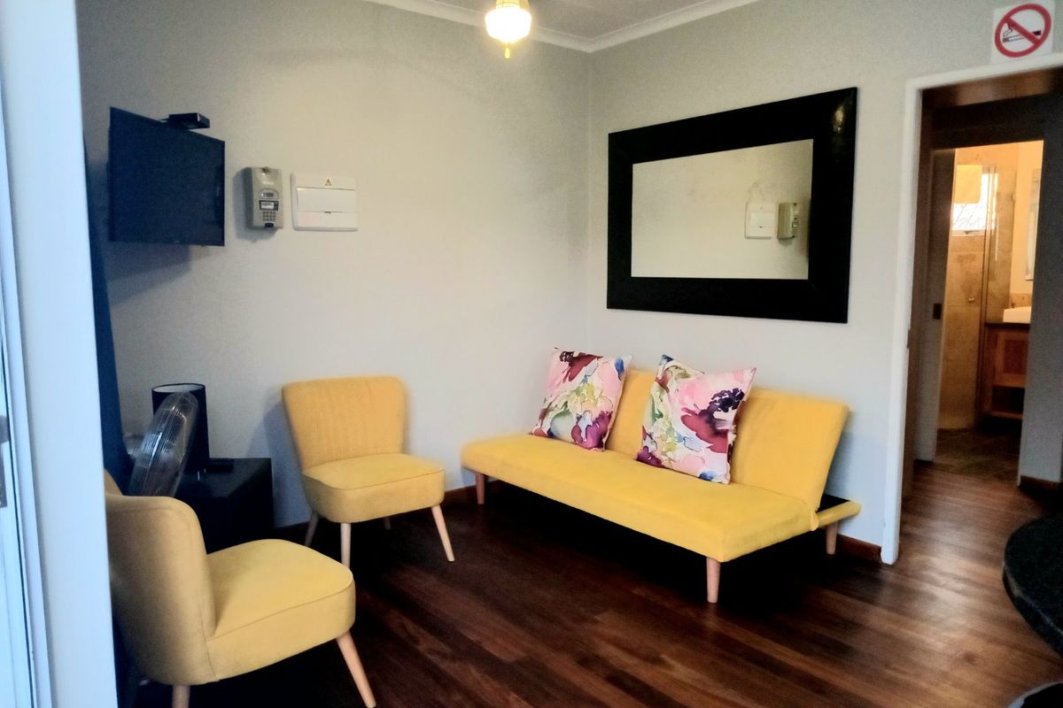 A living room featuring laminate flooring, a ceiling fan, and an integrated intercom system, with a doorway leading to an adjacent bathroom.