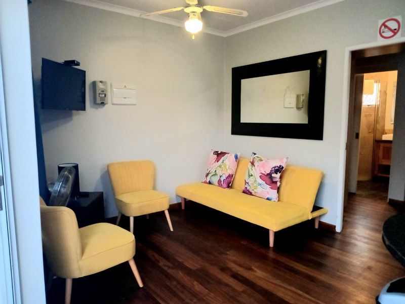 A living room featuring laminate flooring, a ceiling fan, and an integrated intercom system, with a doorway leading to an adjacent bathroom.