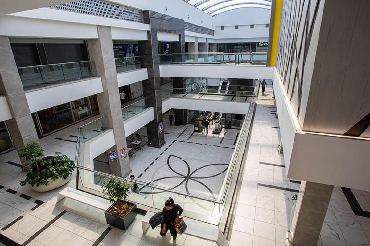 Modern multi-level commercial atrium featuring high-end marble flooring, glass balustrades, and a large skylight providing ample natural light.