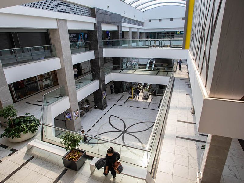 Modern multi-level commercial atrium featuring high-end marble flooring, glass balustrades, and a large skylight providing ample natural light.