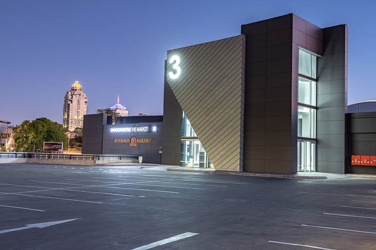 Modern commercial building exterior featuring a paved parking area, contemporary architectural facade, and prominent signage at dusk.