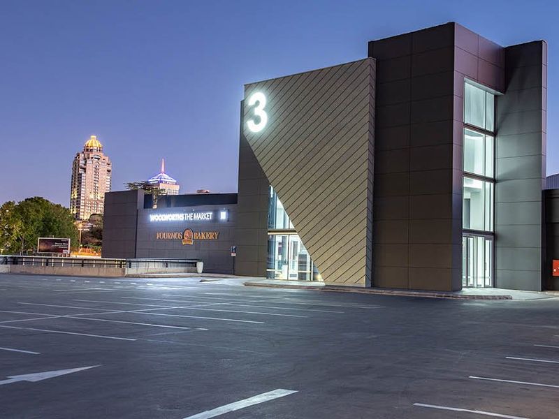 Modern commercial building exterior featuring a paved parking area, contemporary architectural facade, and prominent signage at dusk.