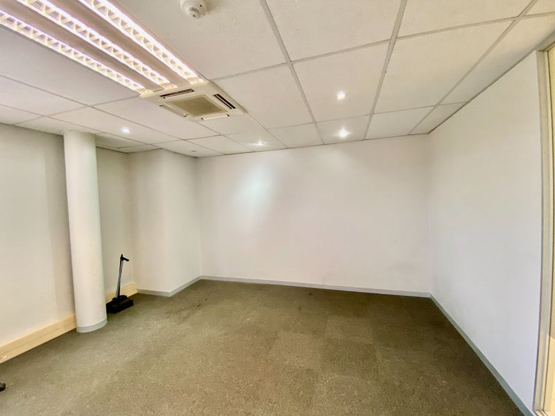 An empty commercial office space featuring a suspended ceiling with recessed lighting, air conditioning, and carpeted flooring.