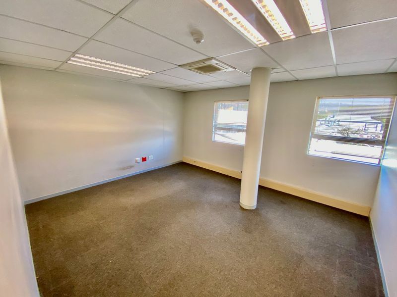 A vacant commercial office space featuring a suspended ceiling, recessed lighting, structural column, and carpeted flooring with integrated data and power points.