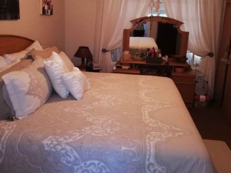 A bedroom featuring a ceiling fan, curtain rod, and built-in storage space.