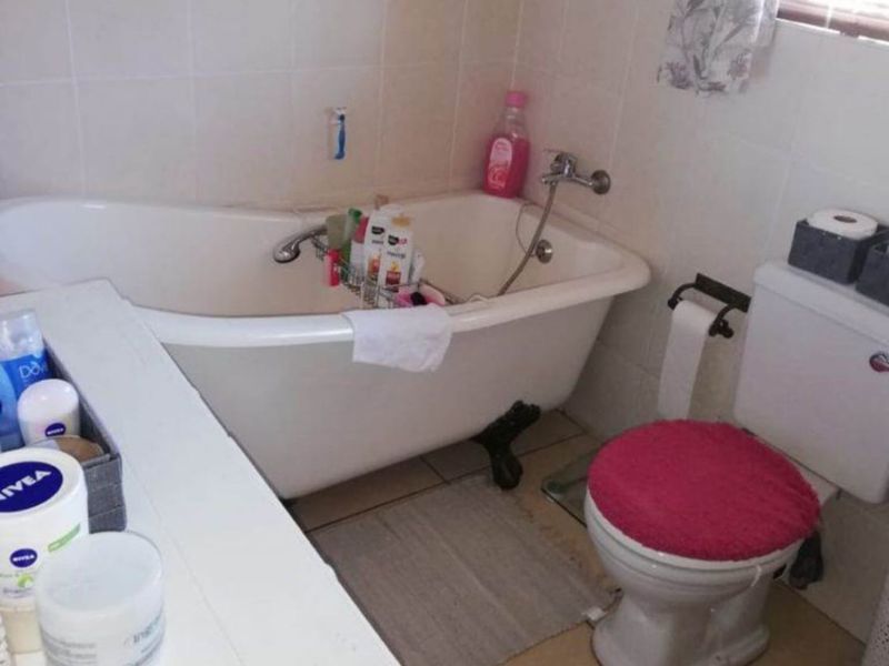 A functional bathroom featuring a classic clawfoot bathtub, ceramic toilet, and tiled finishes, offering a traditional aesthetic ready for potential modernization.
