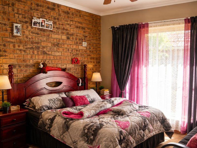 A well-maintained bedroom featuring an exposed brick feature wall, a ceiling fan, and direct access to the outdoors via a sliding glass door.