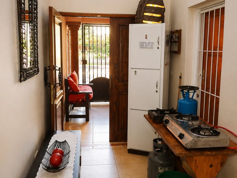 A functional scullery or utility area featuring tiled flooring, decorative chandelier lighting, and direct access to an outdoor patio through a wooden door.