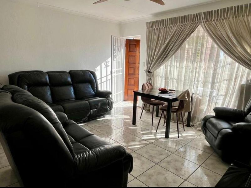Open-plan living and dining area featuring ceramic floor tiles, a ceiling fan, and direct access to the exterior through a sliding glass door.
