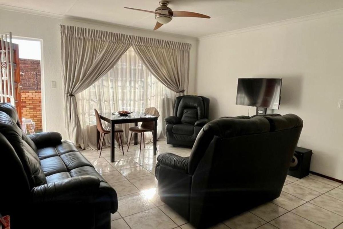 A living room featuring tiled flooring, a ceiling fan, and a sliding glass door providing access to the exterior.