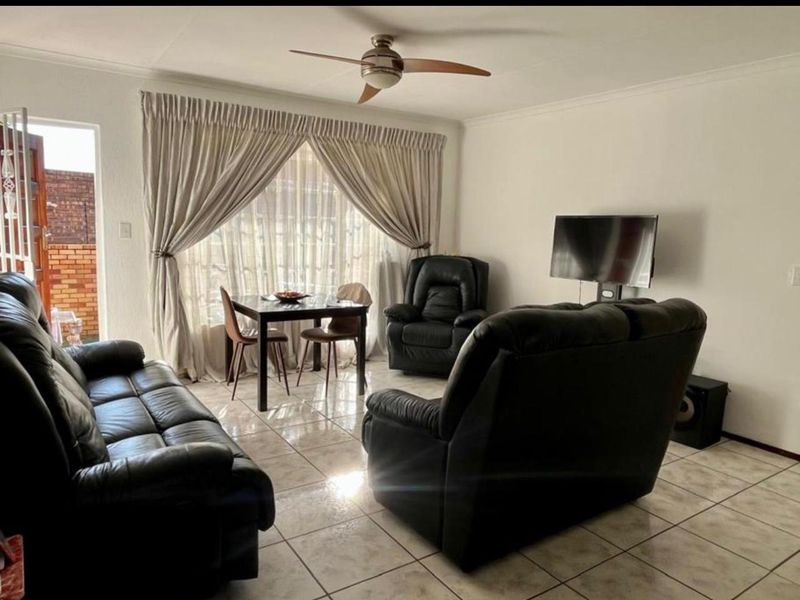 A living room featuring tiled flooring, a ceiling fan, and a sliding glass door providing access to the exterior.