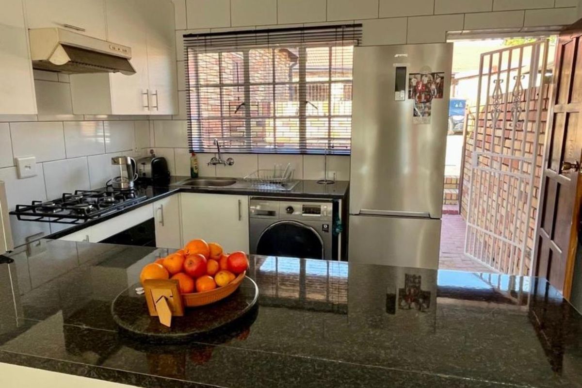 Compact kitchen featuring granite countertops, gas hob, extractor fan, built-in oven, and tiled backsplash with direct access to the exterior.