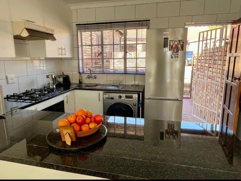 Compact kitchen featuring granite countertops, gas hob, extractor fan, built-in oven, and tiled backsplash with direct access to the exterior.