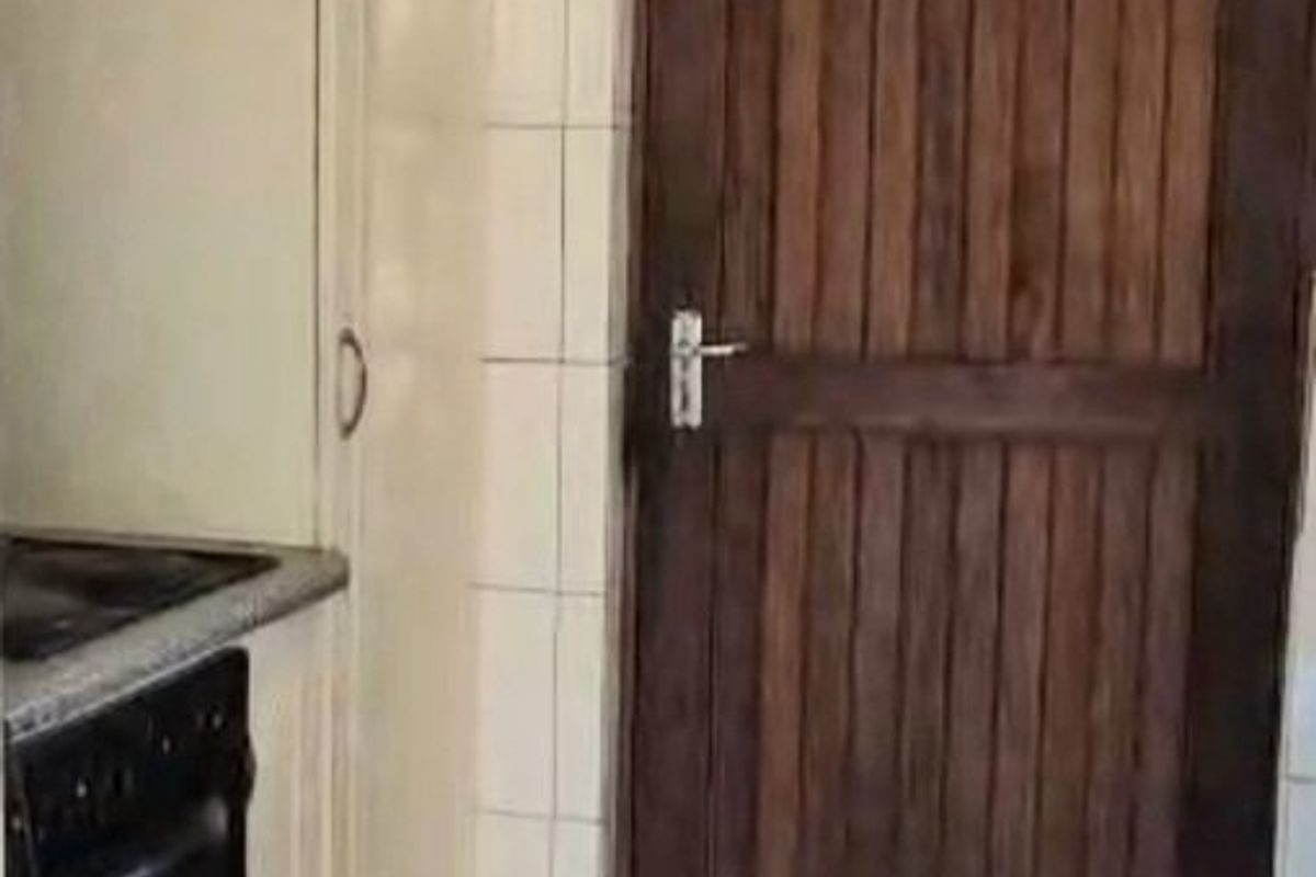 A compact kitchen area featuring built-in cabinetry, an integrated oven, extractor fan, and tiled flooring, presenting an opportunity for modern renovation.