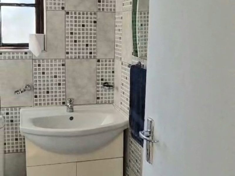 A compact bathroom featuring a vanity cabinet with a basin, tiled walls, and tiled flooring.