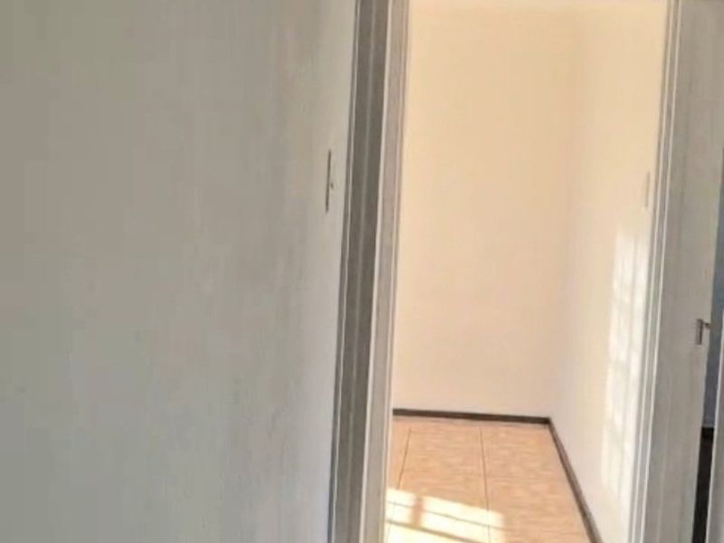 A vacant hallway featuring tiled flooring and decorative ceiling cornicing, leading into an adjacent room.