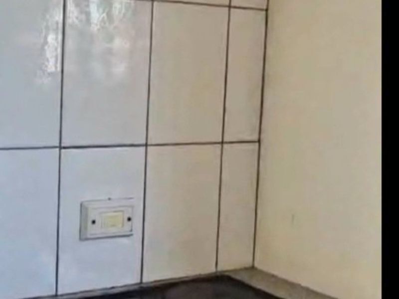 A compact kitchen cooking area featuring a built-in oven, electric hob, extractor fan, and tiled splashback with a laminate countertop.
