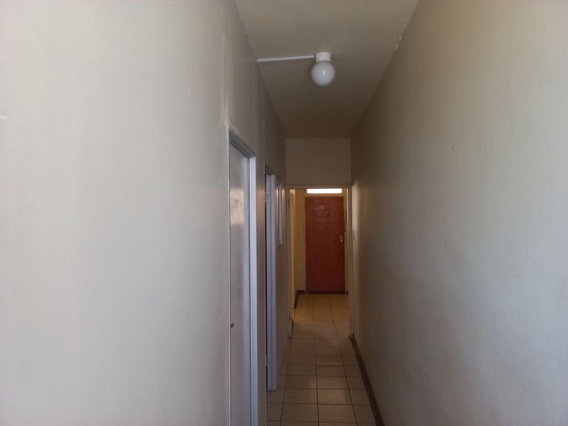 A functional apartment hallway featuring tiled flooring and multiple internal door access points, requiring minor cosmetic updates to improve the overall aesthetic.