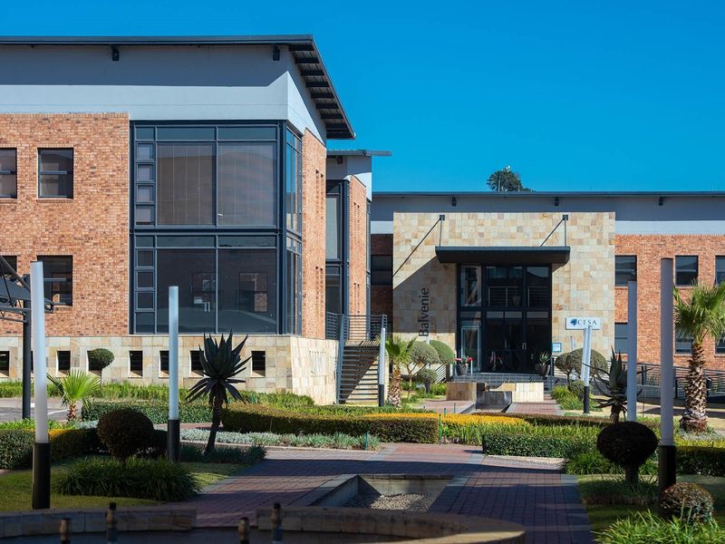Professional exterior view of a modern commercial office building featuring face brick and stone cladding, large glass windows, and a well-maintained landscaped courtyard.