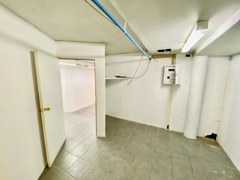 A functional utility space featuring tiled flooring, an exposed electrical distribution board, and overhead fluorescent lighting, suitable for storage or technical use.