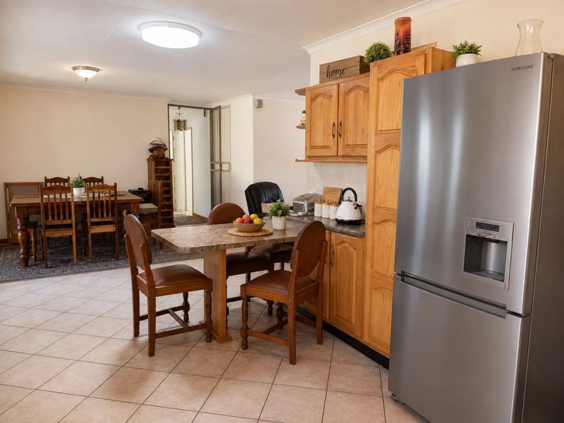 Open plan kitchen and dining area featuring tiled flooring, wooden cabinetry, and a breakfast nook, creating a functional and connected living space.