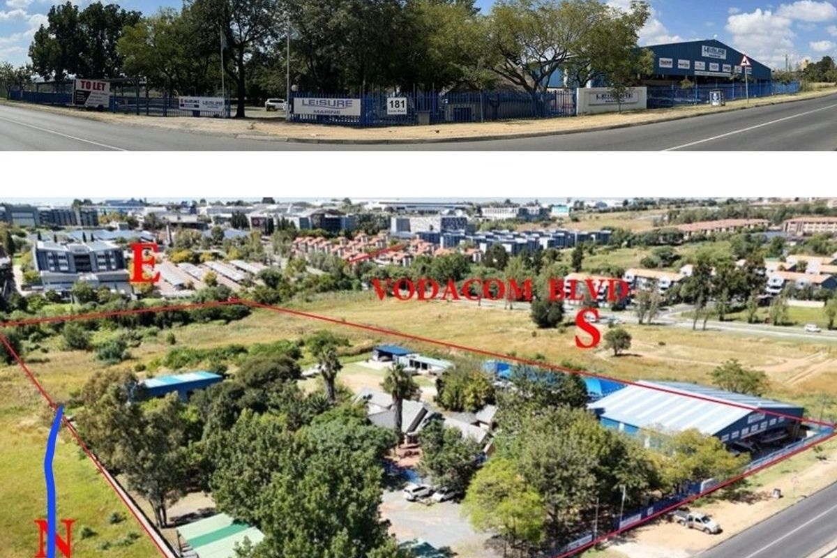 Aerial view of a commercial property site featuring multiple warehouse structures, perimeter fencing, and mature landscaping, situated at a prominent road intersection.