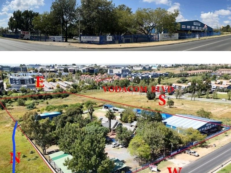 Aerial view of a commercial property site featuring multiple warehouse structures, perimeter fencing, and mature landscaping, situated at a prominent road intersection.