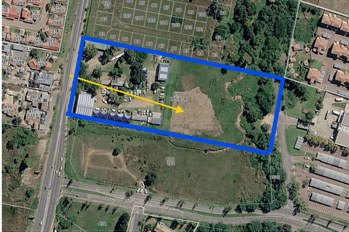 Aerial view of a commercial property plot with existing structures and significant undeveloped land, highlighting site boundaries and access.