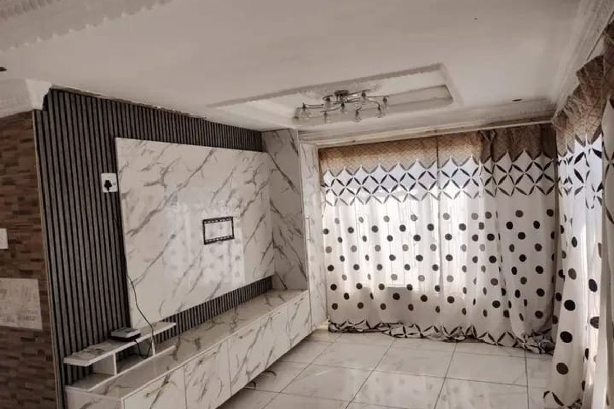 Living room featuring a custom built-in media unit with marble-effect finish, slatted wall detailing, recessed ceiling tray, and tiled flooring.