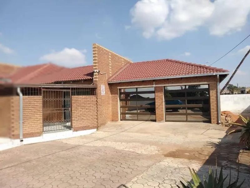 Front exterior view of a face brick house featuring a double garage with modern glass-panel doors and a paved driveway.