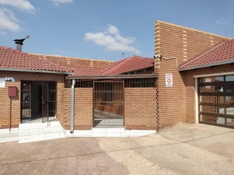 Front exterior view of a face brick house featuring a tiled roof, security gate, and integrated garage with paved driveway access.