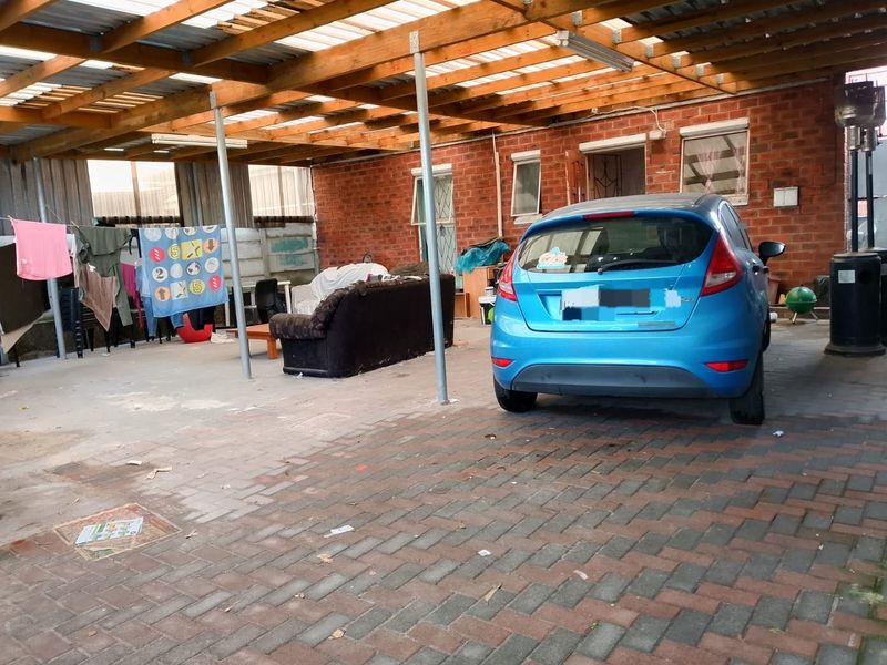 A covered outdoor patio area featuring a timber pergola structure, brick walls, and paved flooring, suitable for use as an entertainment or utility space.