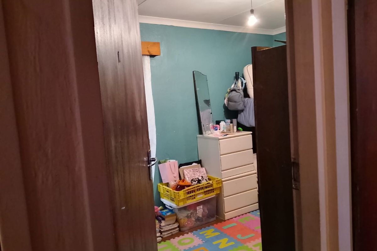 A view into a bedroom featuring painted walls and a timber door, currently used as a storage and play area.