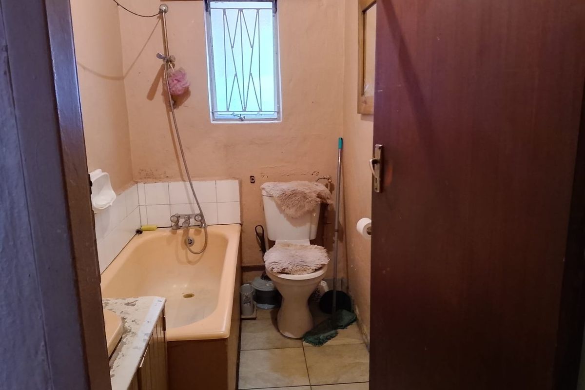 A dated bathroom featuring a bathtub, toilet, and vanity, requiring cosmetic updates and modernization of fixtures to improve the overall condition.