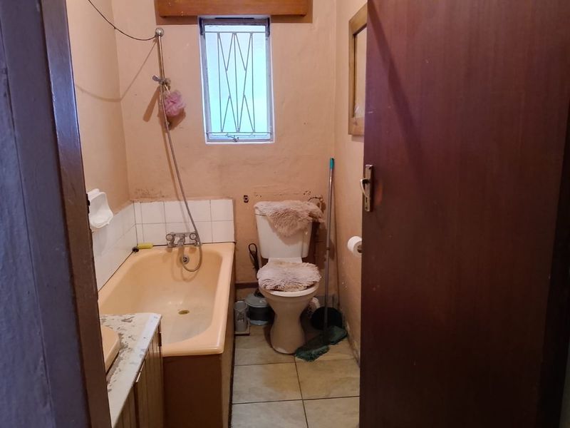 A dated bathroom featuring a bathtub, toilet, and vanity, requiring cosmetic updates and modernization of fixtures to improve the overall condition.