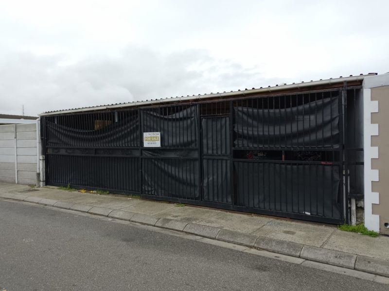 Street-facing view of the property featuring a large metal security gate and boundary wall with a for sale sign.
