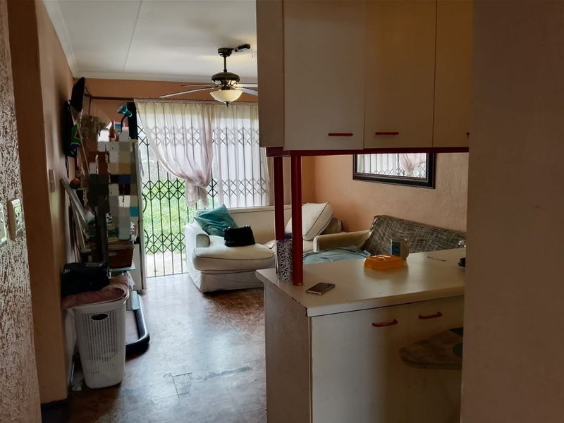 Open plan living area featuring a breakfast bar, built-in cabinetry, and a ceiling fan, with direct access to the exterior through a security gate.
