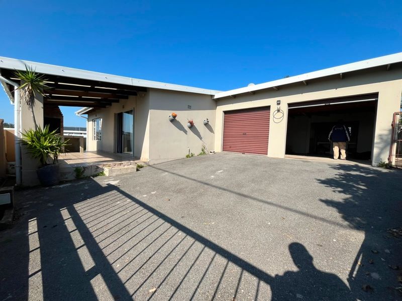 Front exterior view featuring an asphalt driveway, double garage, and a covered patio area with a built-in braai.