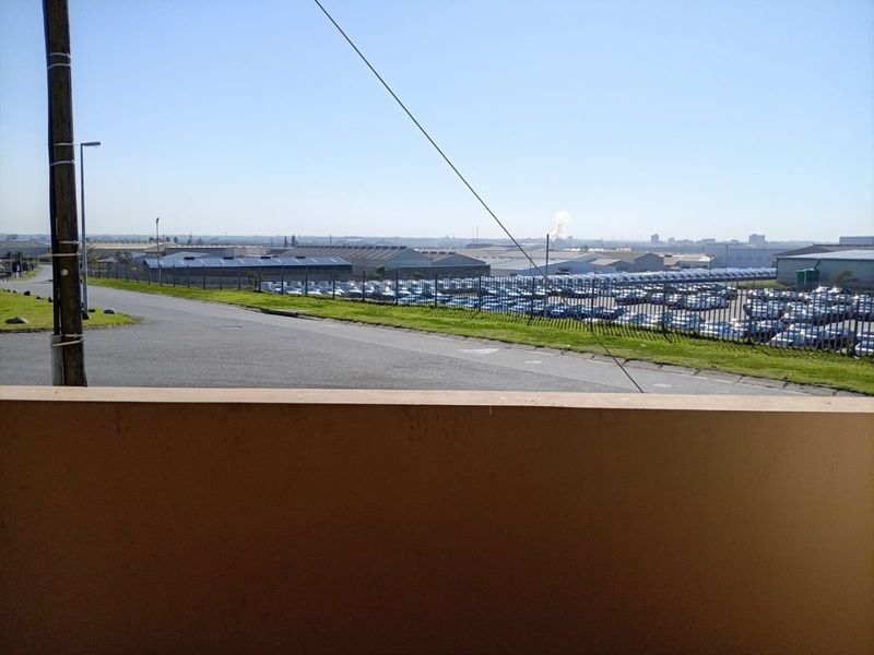 An elevated view overlooking a commercial or industrial area with extensive vehicle storage and surrounding infrastructure.