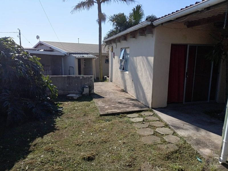 Rear exterior view of the property featuring a concrete patio, sliding door access, and a garden area with a stone pathway.
