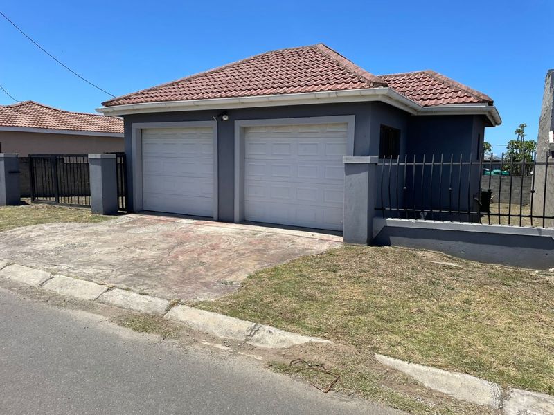 A detached double garage featuring a tiled roof, secure perimeter fencing, and a concrete driveway.