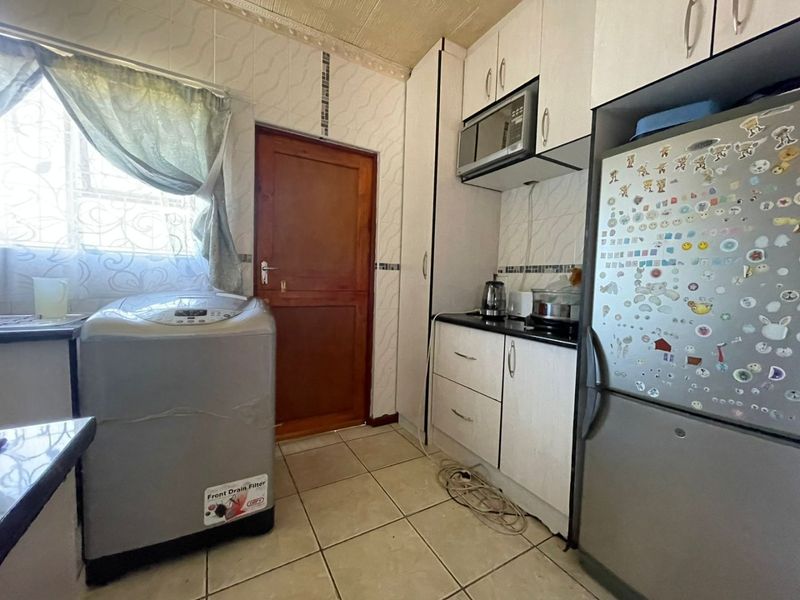 A functional laundry area featuring built-in cabinetry, tiled flooring, and a tiled backsplash, providing practical utility space with direct exterior access.