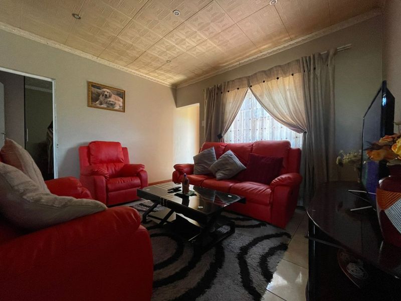 A comfortable living room featuring tiled flooring, recessed downlighting, and a decorative textured ceiling finish.