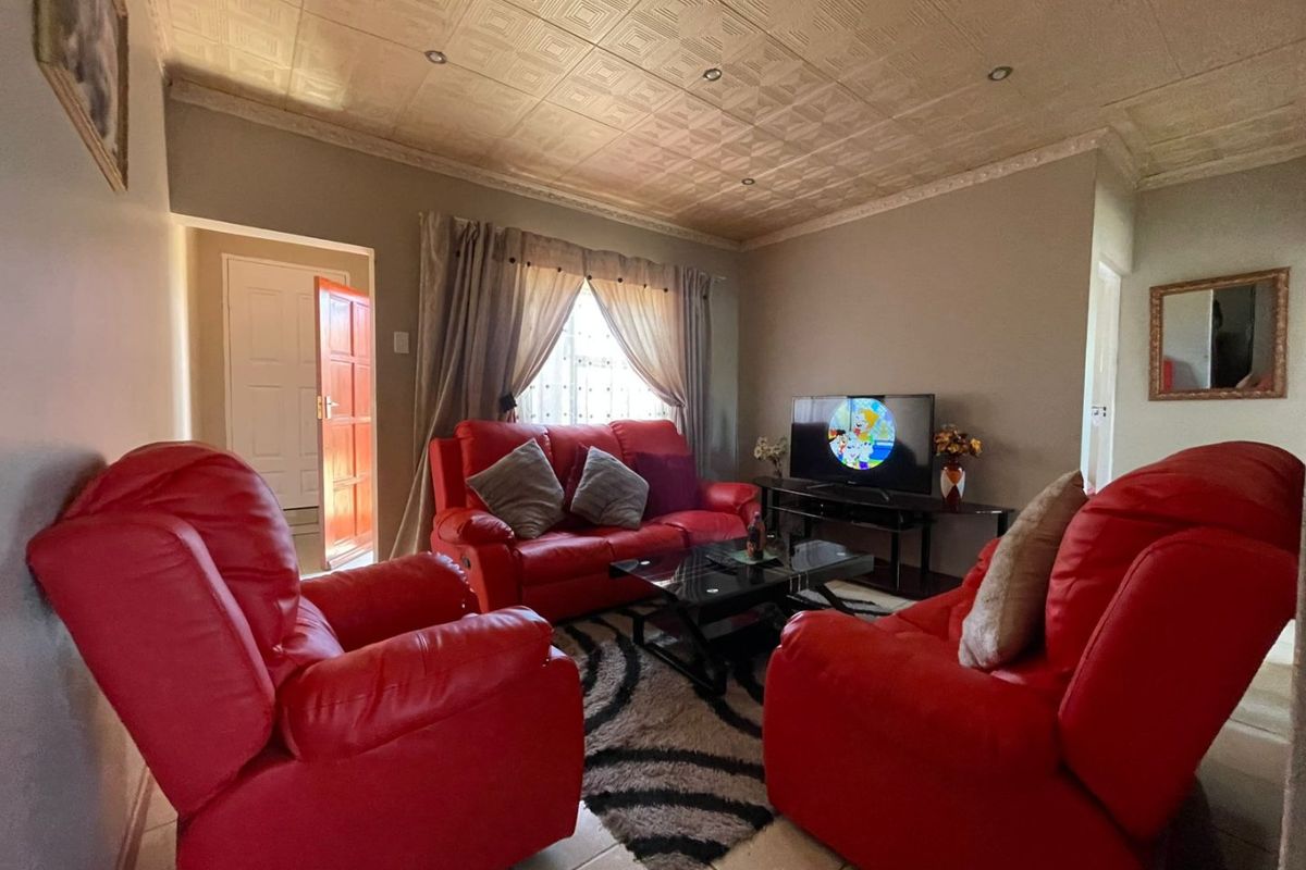 A comfortable living room featuring tiled flooring, decorative textured ceiling tiles, and recessed lighting, providing a functional and well-lit space for relaxation.