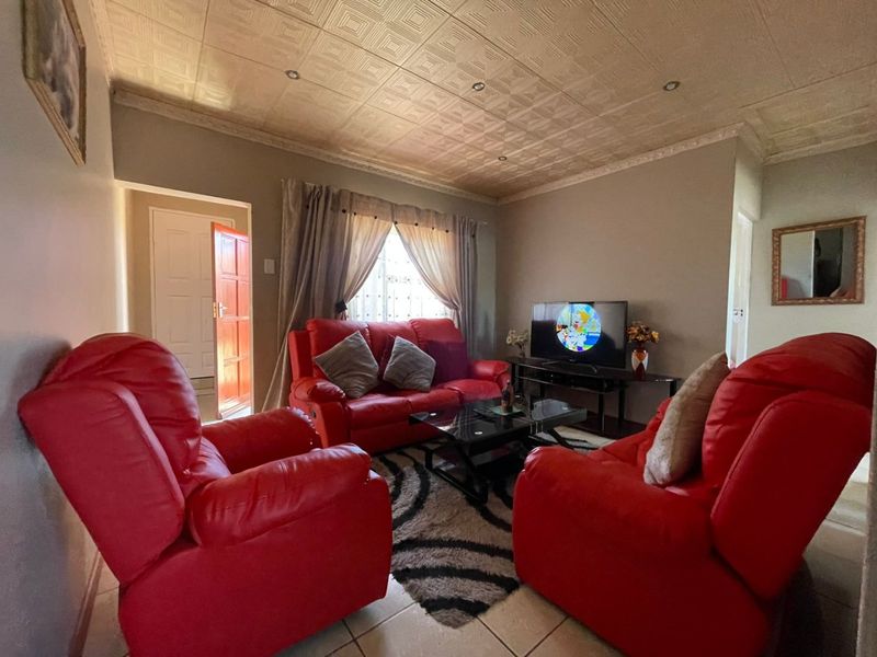 A comfortable living room featuring tiled flooring, decorative textured ceiling tiles, and recessed lighting, providing a functional and well-lit space for relaxation.